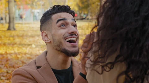 Close-up portrait hispanic young guy kneeling in front of girlfriend outdoors Stock Footage 165826029