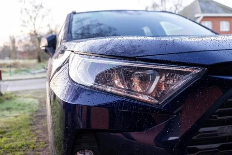 A close up portrait of the left headlight of a dark blue hybrid toyota rav4.. Stock Photos