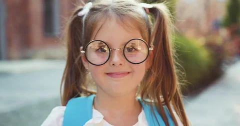 Close up. Portrait of lovely small school girl in glasses with backpack smiling Stock Footage 249598857