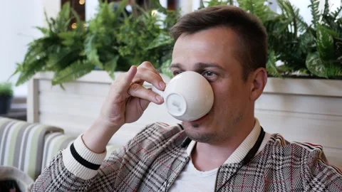 Close up portrait man in cafe talking to someone and drinking tea or coffee Stock Footage 139937923