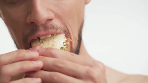 Close-up portrait of man eagerly eat fish sandwich on white background close up Stock Footage 147612748