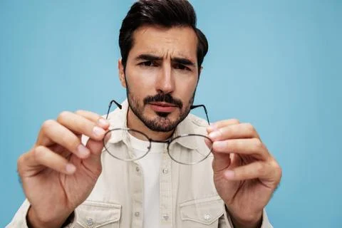 Close-up portrait of a man looking through glasses that he holds in his hands Stock Photos