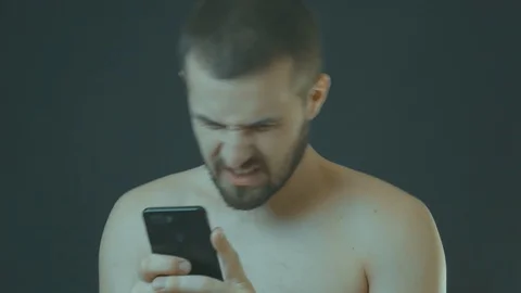 Close-up portrait of a man surprised and angry looking at his mobile phone 스톡 동영상 122848757