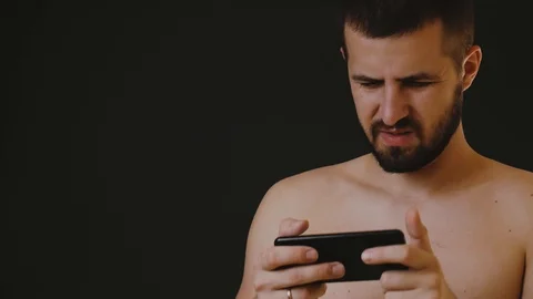 Close-up portrait of a man surprised and angry looking at his mobile phone Stock Footage 122848837