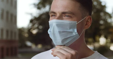 Close-up portrait man young guy student model patient puts on blue protective Stock Footage 140999697