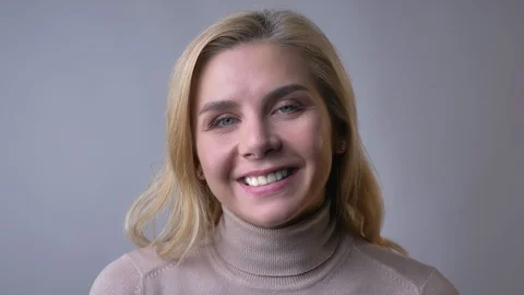 Close-up portrait of middle-aged blonde female watching and smiling happily into Stock Footage 99397350