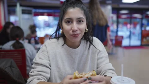 Close-up portrait of multi-race brunette beautiful, happy woman eating burger Stock Footage 293490931