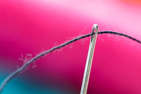 A close up portrait of a needle with a black thread running through the eye o Stock Photos