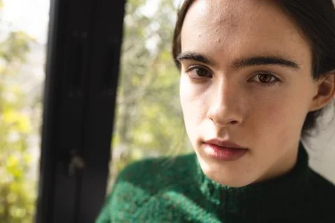 Close up portrait of non-binary trans woman standing hear the window at home Stock Photos