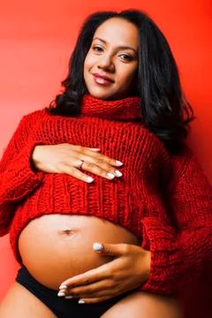 Close up portrait of pregnant woman with big belly, hands hold, red sweater on Stock Photos