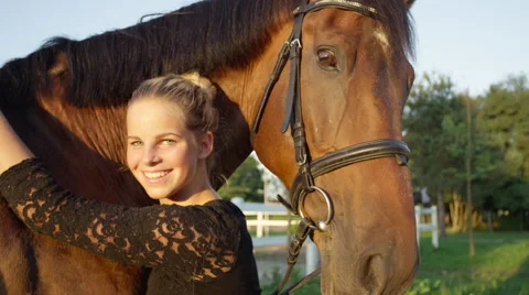 CLOSE UP: Portrait of pretty smiling girl embracing her brown horse on sunny day Stock Footage
