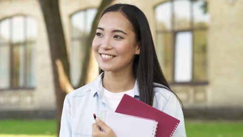 Close up portrait of pretty smiling student girl holding textbooks. Stock Footage 114266568