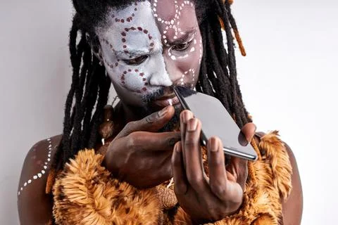 Close-up portrait of primitive african guy studying the surface of smartphone Stock Photos