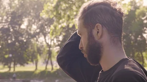 Close-up portrait in a profile of a young bearded man which smoothes his beard Stock Footage 99022590