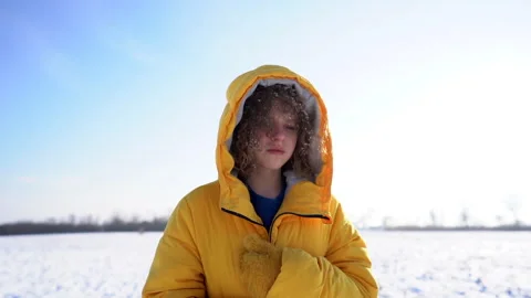 Close-up portrait of a sad curly-haired schoolgirl walking in a snowy field in a Stock Footage 147941611