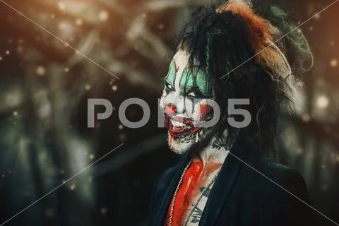 Close-up portrait of a scary punk clown man smeared with blood in a night for Stock Photos