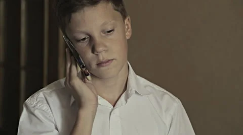 Close-up portrait of a schoolboy talking over telephone Video stock 67717923