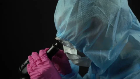 Close-up portrait of scientist in a protective suit checks samples by microscope Stock Footage 129206147