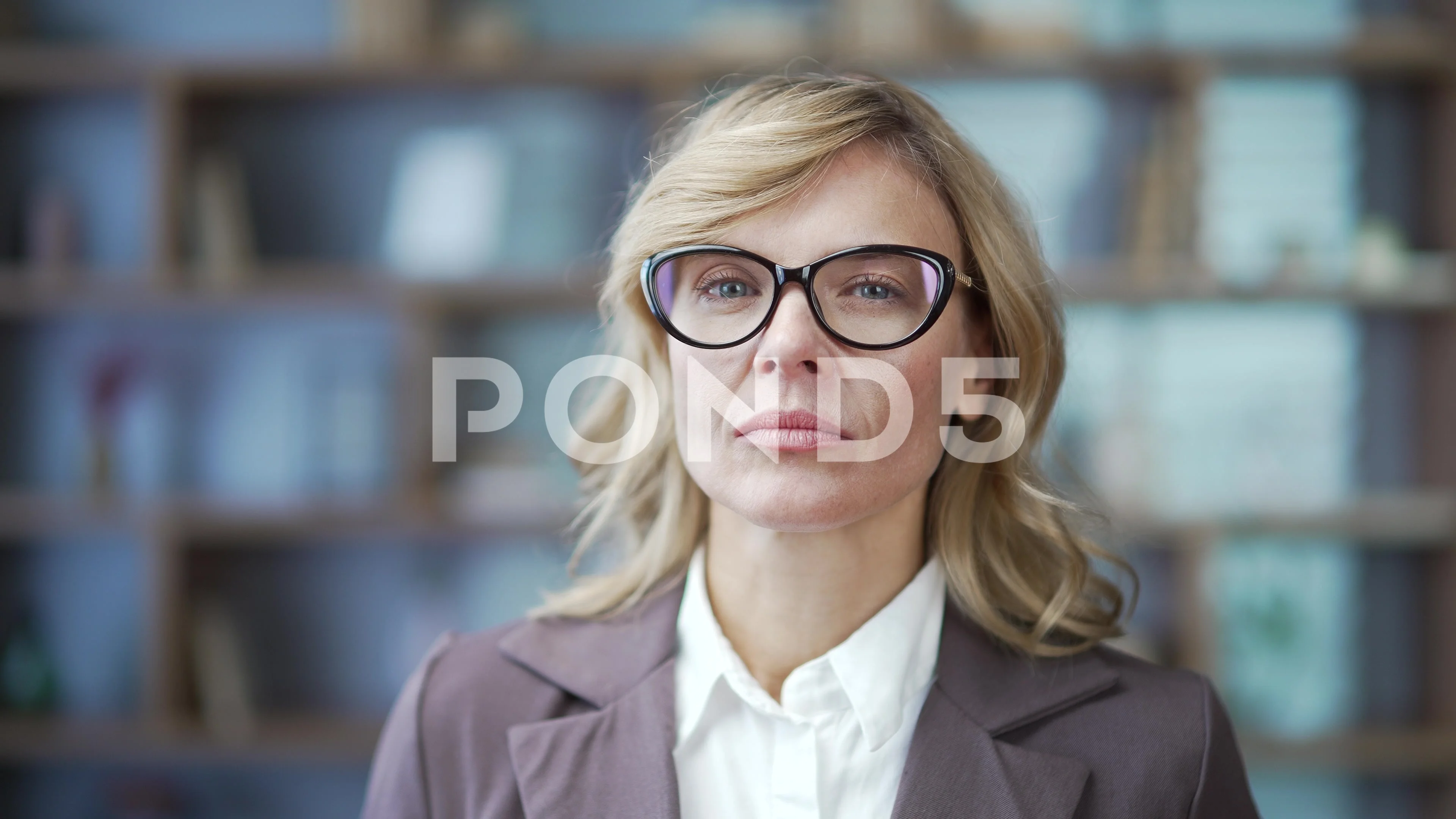 Close up portrait of serious mature businesswoman in glasses and suit  looking