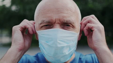 Close up Portrait of Serious Old Man while He Put on a Medical Face Mask and Stock Footage 148468865