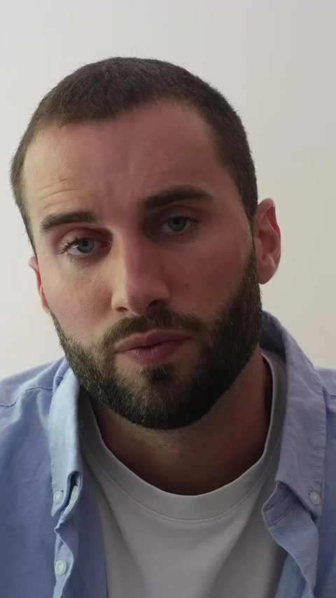 Close-up portrait of a serious young man with a beard and blue eyes talking Stock Footage 344782111
