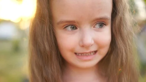 A close portrait of a small, perky long-haired girl. The child laughs, showing Stock Footage 95122070