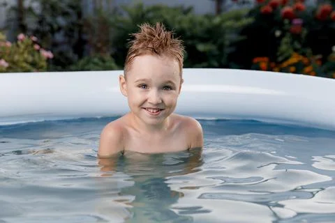 Close-up portrait of a smiling five-year-old boy having fun in a blue pool Stock Photos