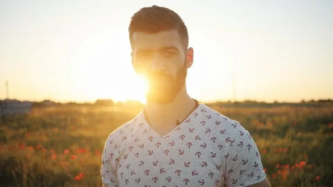 Close up portrait of smiling man standing in green wheat field on sunset and Stock Footage 92065091