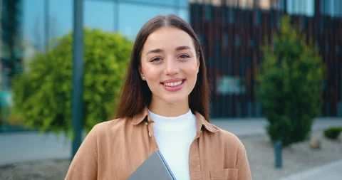 Close-up portrait of a smiling young Caucasian woman standing outdoors near a mo Stock Footage 333636055