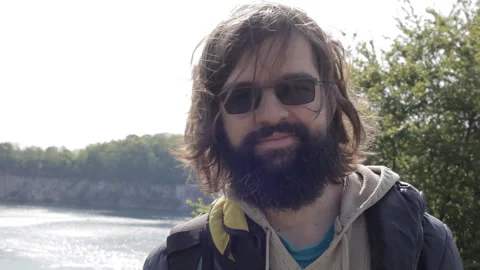 Close-up portrait of a smiling young man with a beard and long brunette hair. Stock-Footage 112641014