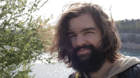 Close-up portrait of a smiling young man with a beard and long brunette hair. Stock-Footage 112641555