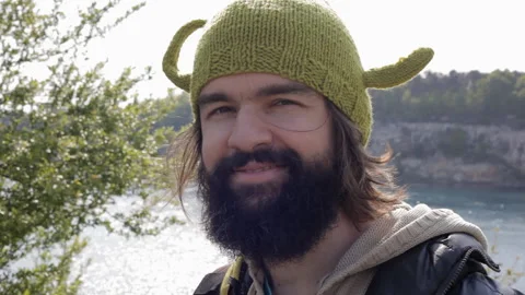 Close-up portrait of a smiling young man with a black beard in a knitted hat. Stock-Footage 113791440