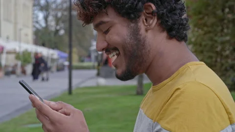 Close-up portrait of smiling young man holding and using mobile phone. Stock Footage 163282181