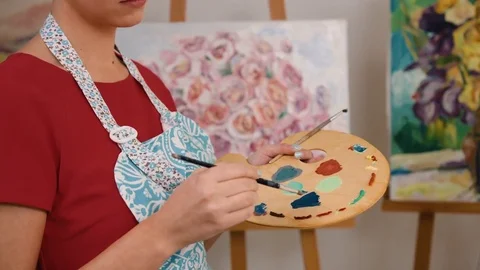 Close up portrait of smiling young painter mixing colors on her palette at her Stock Footage 74194951
