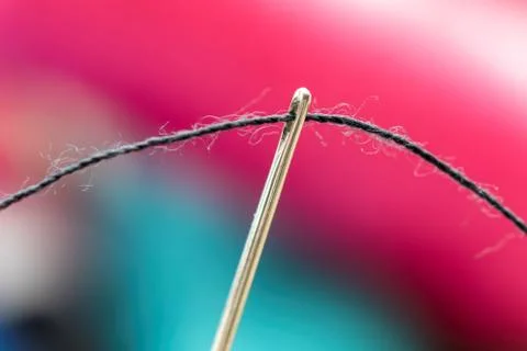 A close up portrait of some sewing thread put through the hole of a needle. T Stock Photos