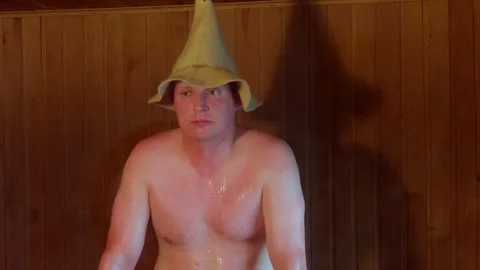 Close up portrait of sweating man wearing traditional felt hat in steam sauna Vidéo 342661173