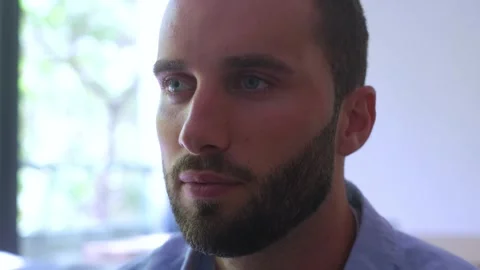 Close-up portrait of a thoughtful young man with a beard and blue eyes Vídeos de archivo 344787084