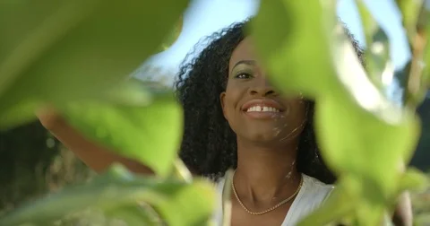 Close-up portrait through plants. Charming afro-american woman with neutral Stock Footage 84508815