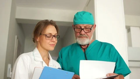 Close portrait of two doctors, a mature man and a young woman, doctors look at Stock Footage 119073262