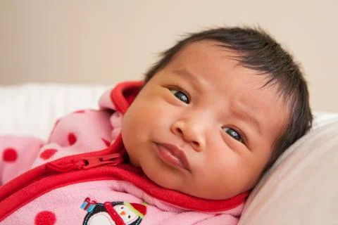 Close-up portrait of two week old Asian baby girl in pink polka dot jacket, Stock Photos