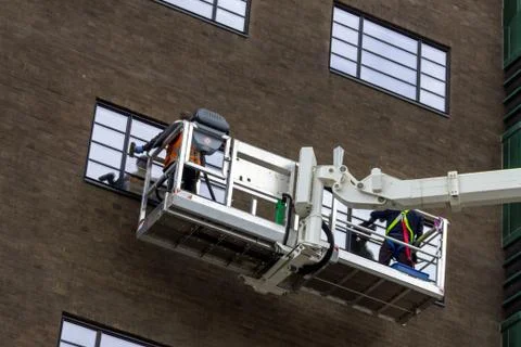 A close up portrait of two window washers, using a crane to get to the top wi Stock Photos