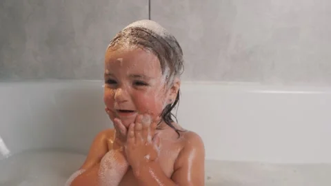 Close-up portrait of a two-year-old girl bathing in a bubble bath Stock Footage 221495866