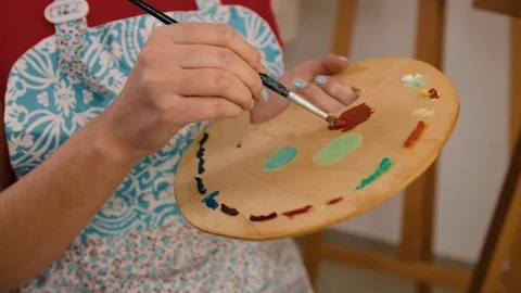 Close up portrait of woman`s hand mixing paint on palette at workshop Stock Footage 74204279