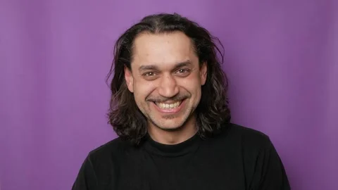 Close-up portrait of a young attractive guy, he laughs and looks at the camera. Stock Footage 250627244