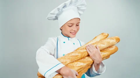 Close up portrait young baker girl child holds bread baguettes and smiling Stock Footage