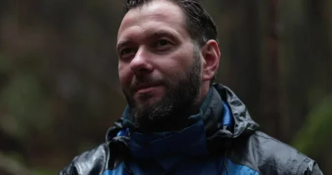 Close-up portrait of a young bearded man sitting in nature between forest Stock Footage 244144331