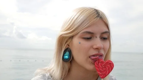 Close-up portrait of a young blonde girl with a splitted tongue, she licks a Stock Footage