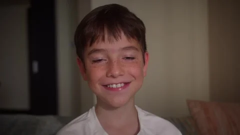 Close up portrait of a young boy smiling and looking at the camera in a cozy Stock Footage 345833981