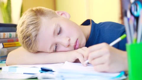 Close-up portrait of a young cute boy, schoolboy lying at the table closes  Stock Footage 138411819
