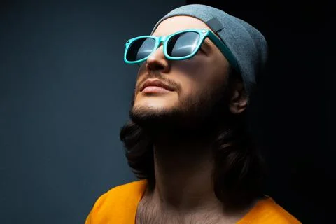 Close-up portrait of young guy looking, wearing cyan sunglasses and grey hat. Stock Photos